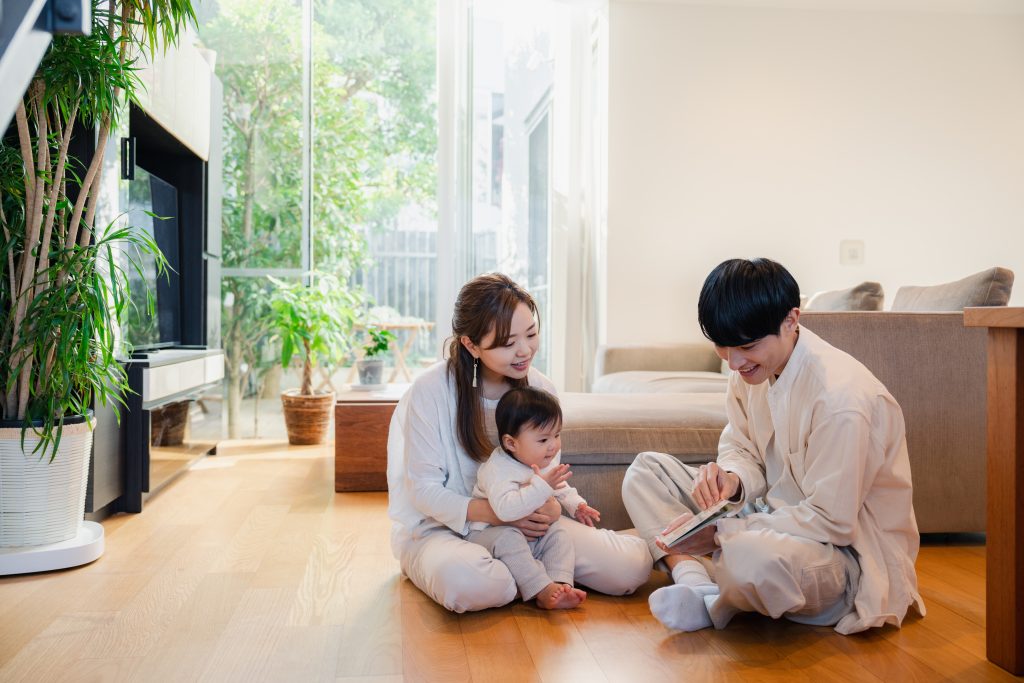 リビングの床に座り、家族3人が自然光の入る空間で穏やかな時間を過ごしている様子