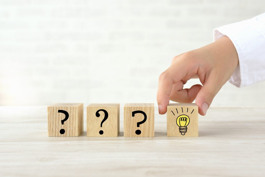 疑問符が描かれた木製ブロックの横に、電球マークのブロックを手で選び取ろうとしている様子